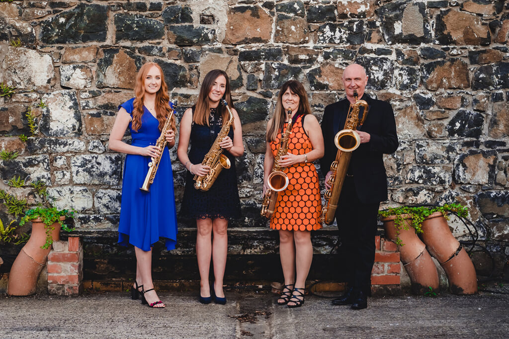 NI Saxaphone Quartet together posed wall background